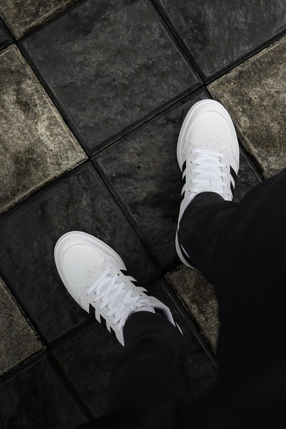 White everyday sneakers against dark city paving